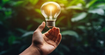 a hand holding a lightbulb with a green background