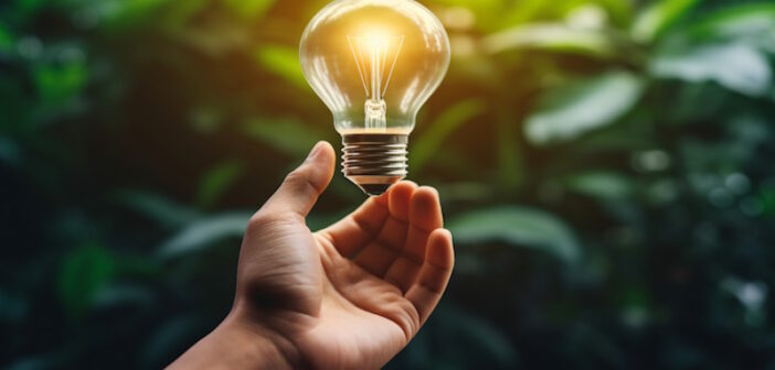 a hand holding a lightbulb with a green background