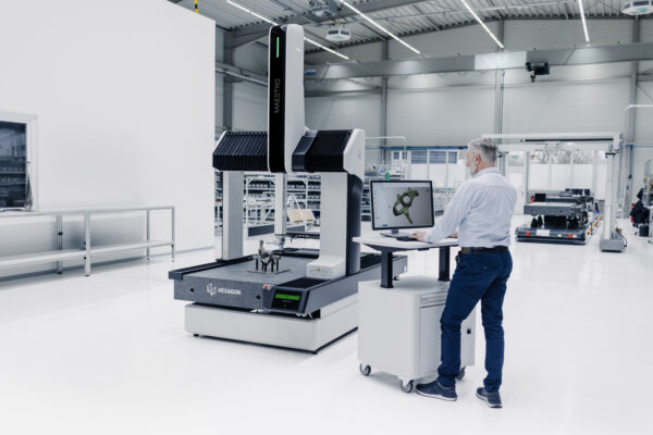 Engineer next to a MAESTRO CMM in a shop floor environment.