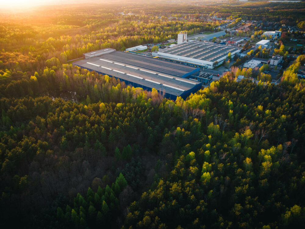 a factory surrounded by trees, symbolising sustainable manufacturing