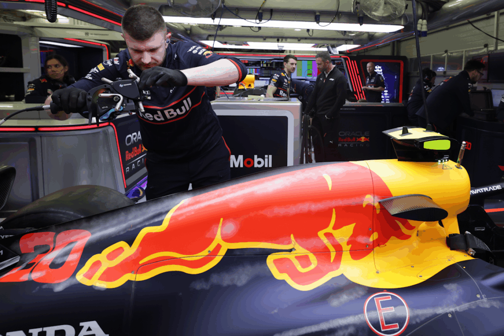 An engineer in Oracle Red Bull Racing clothing peforms a scan on a formula 1 racing car
